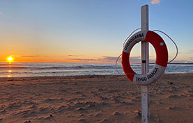 Trygg-Hansas livboj på stranden framför solnedgången