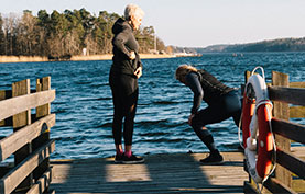 Två kvinnor på en brygga som gör gymnastik bredvid Trygg-Hansas livboj