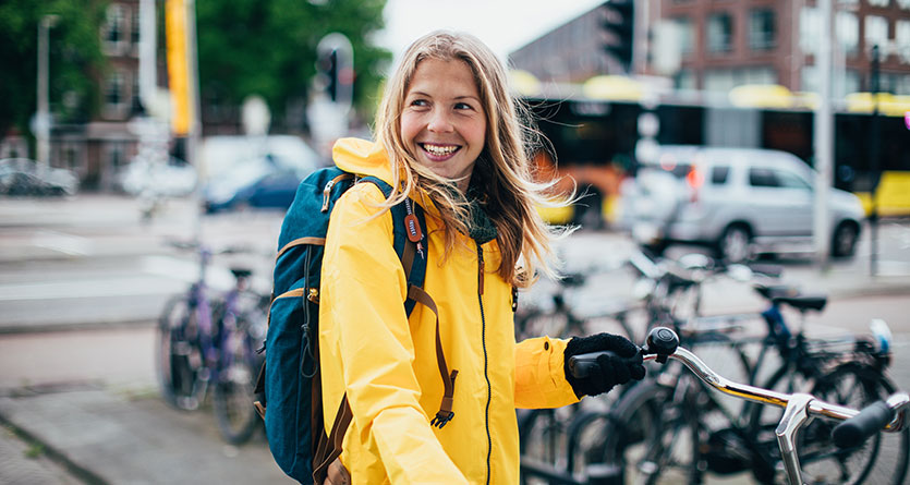 Kvinna i gul jacka håller i cykel