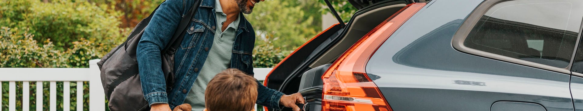 Glad pappa och son packar in väskor i ett bagageutrymmet på bilen