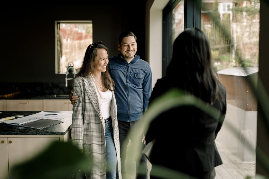 Man och kvinna är på visning i ett hus och pratar med en mäklare
