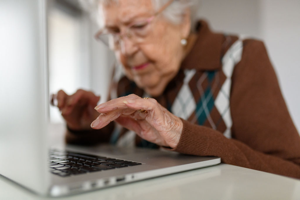 Äldre kvinna skriver på ett tangentbord på sin desktop