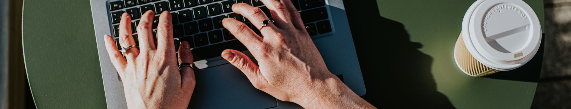 Kvinna sitter utomhus och skriver på sin laptop