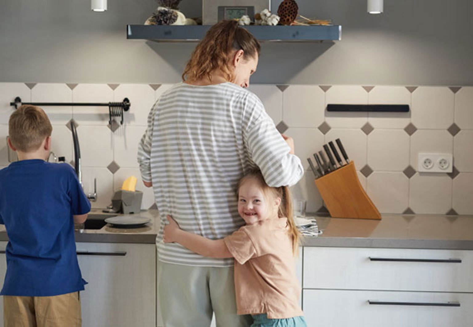 mamma med sina två barn i köket
