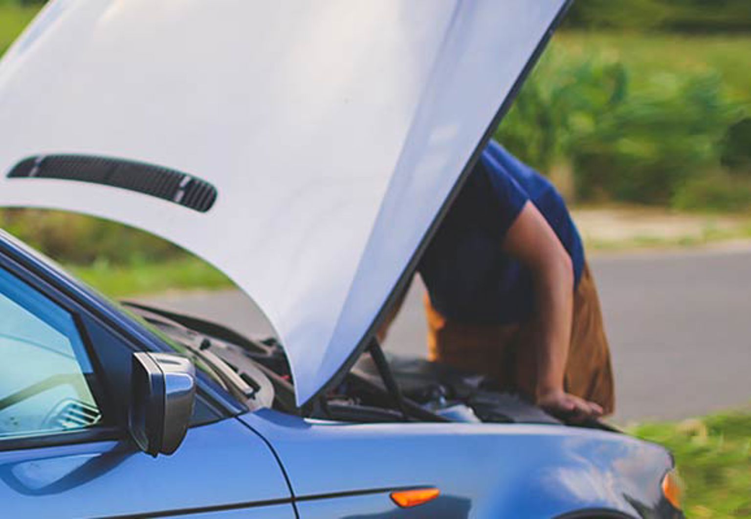 en person tittar under huven på sin bil