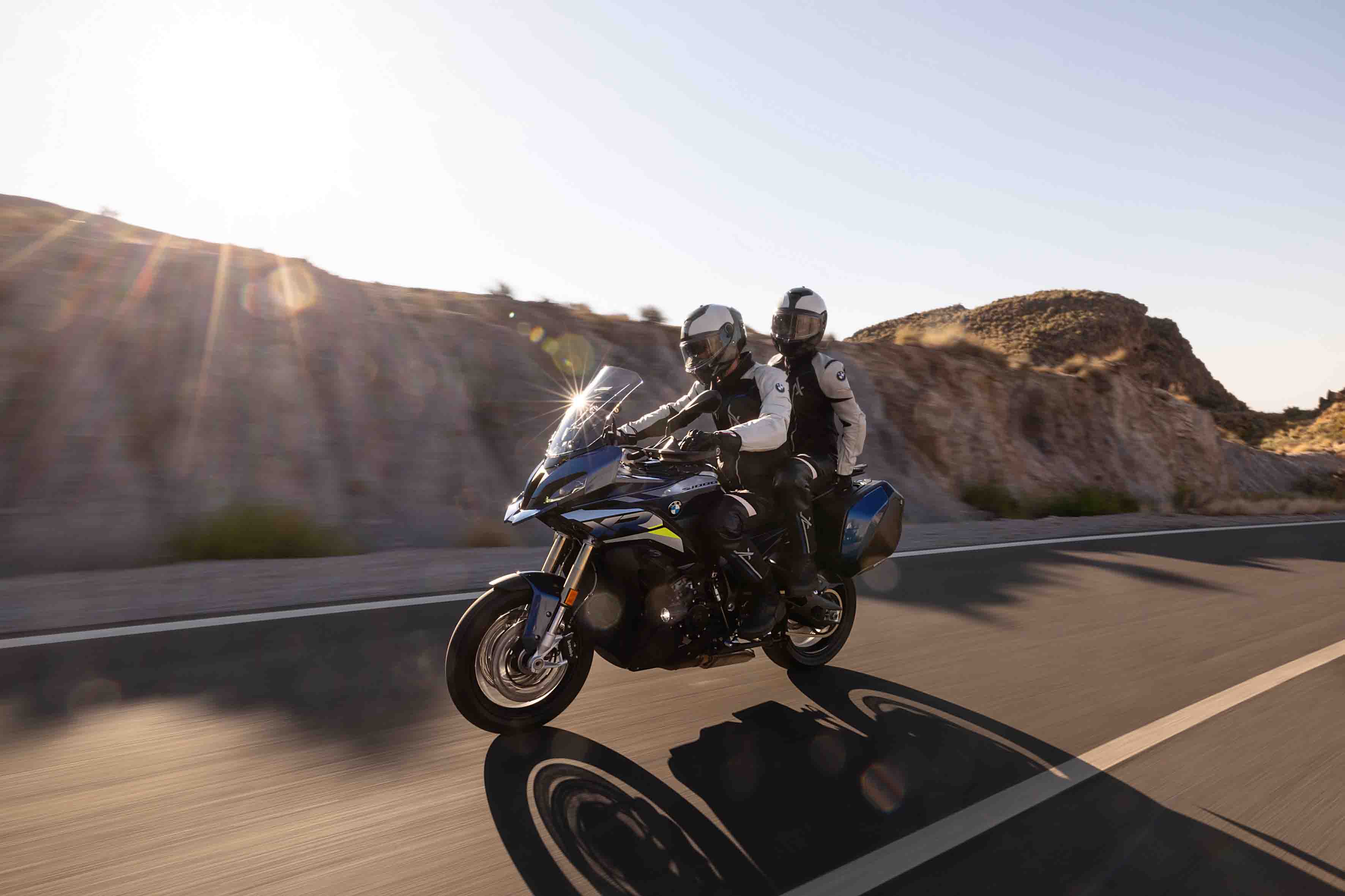 Två människor åker på en BMW-motorcykel bland höga berg