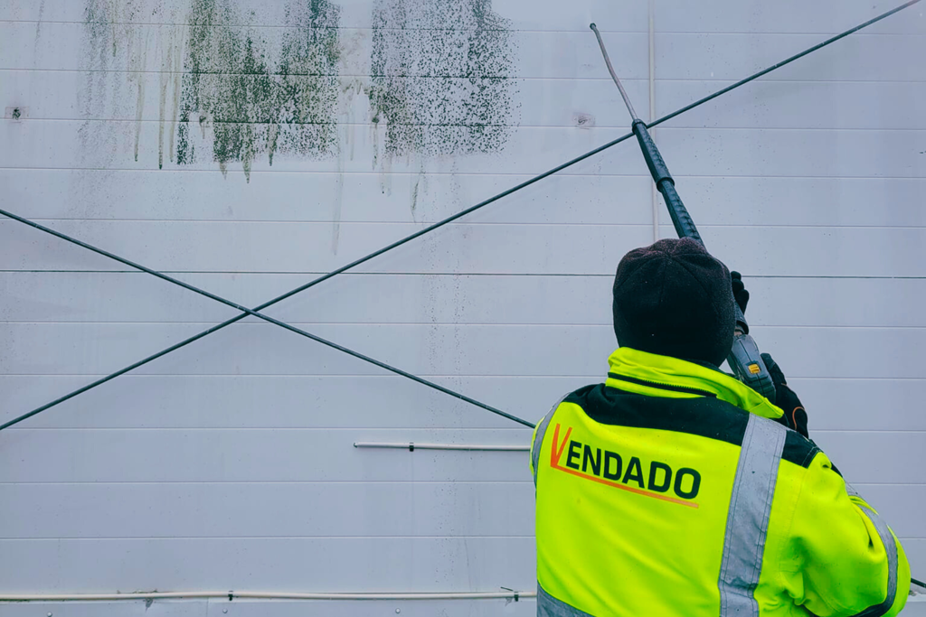 man rengör en vägg med högtrycksspruta