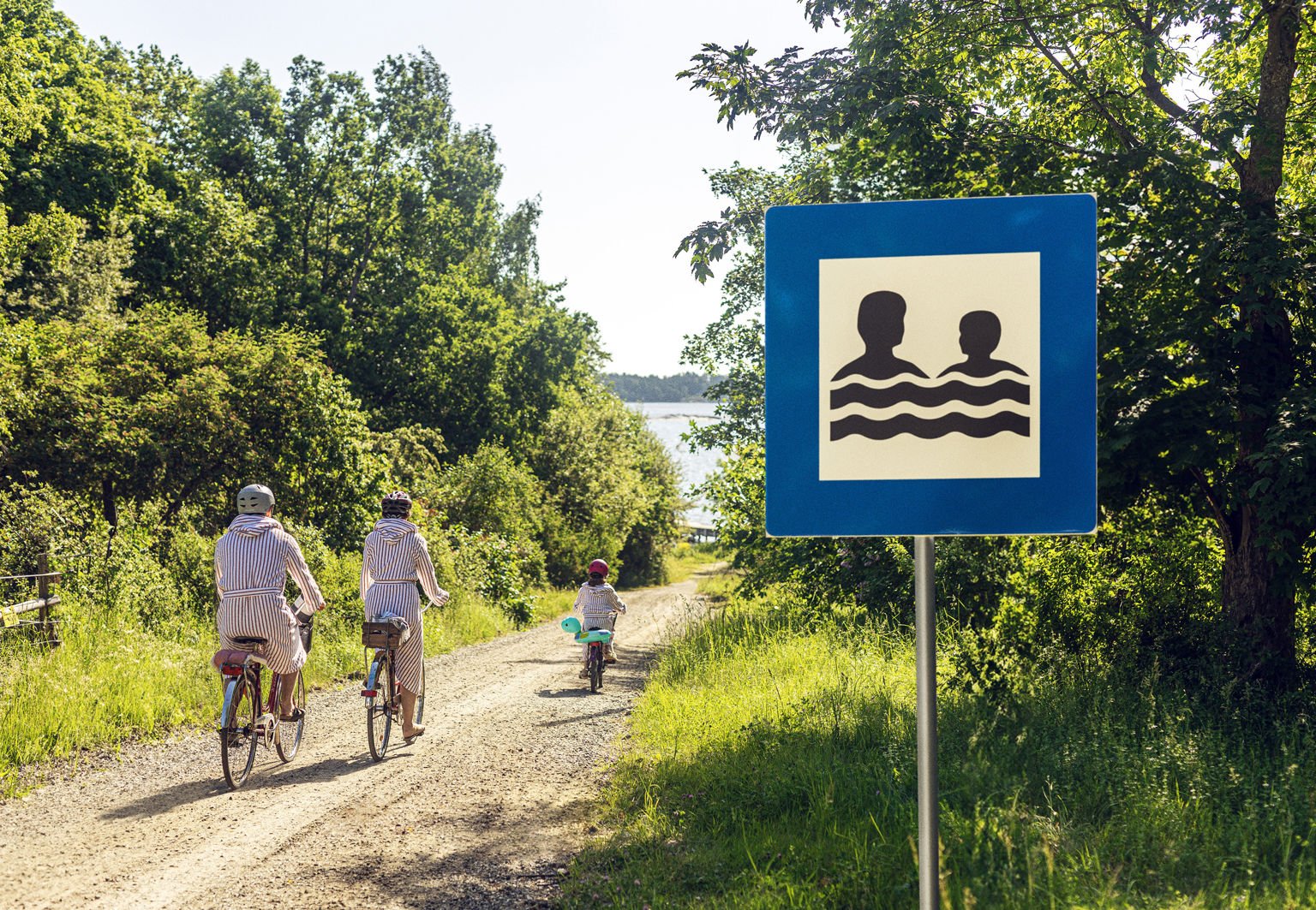 familj cyklar förbi skylten bada tillsammans