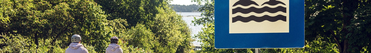 familj cyklar förbi skylten bada tillsammans