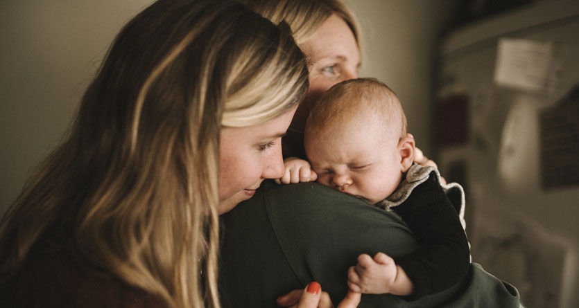 Mammor som håller sin bebis i famnen