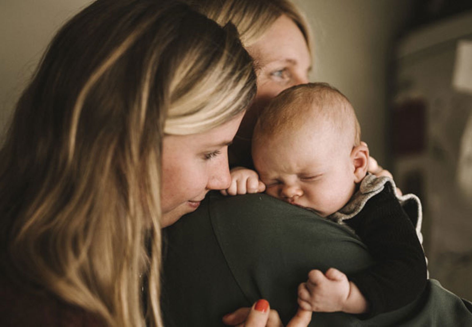 två kvinnor med en bebis kramas