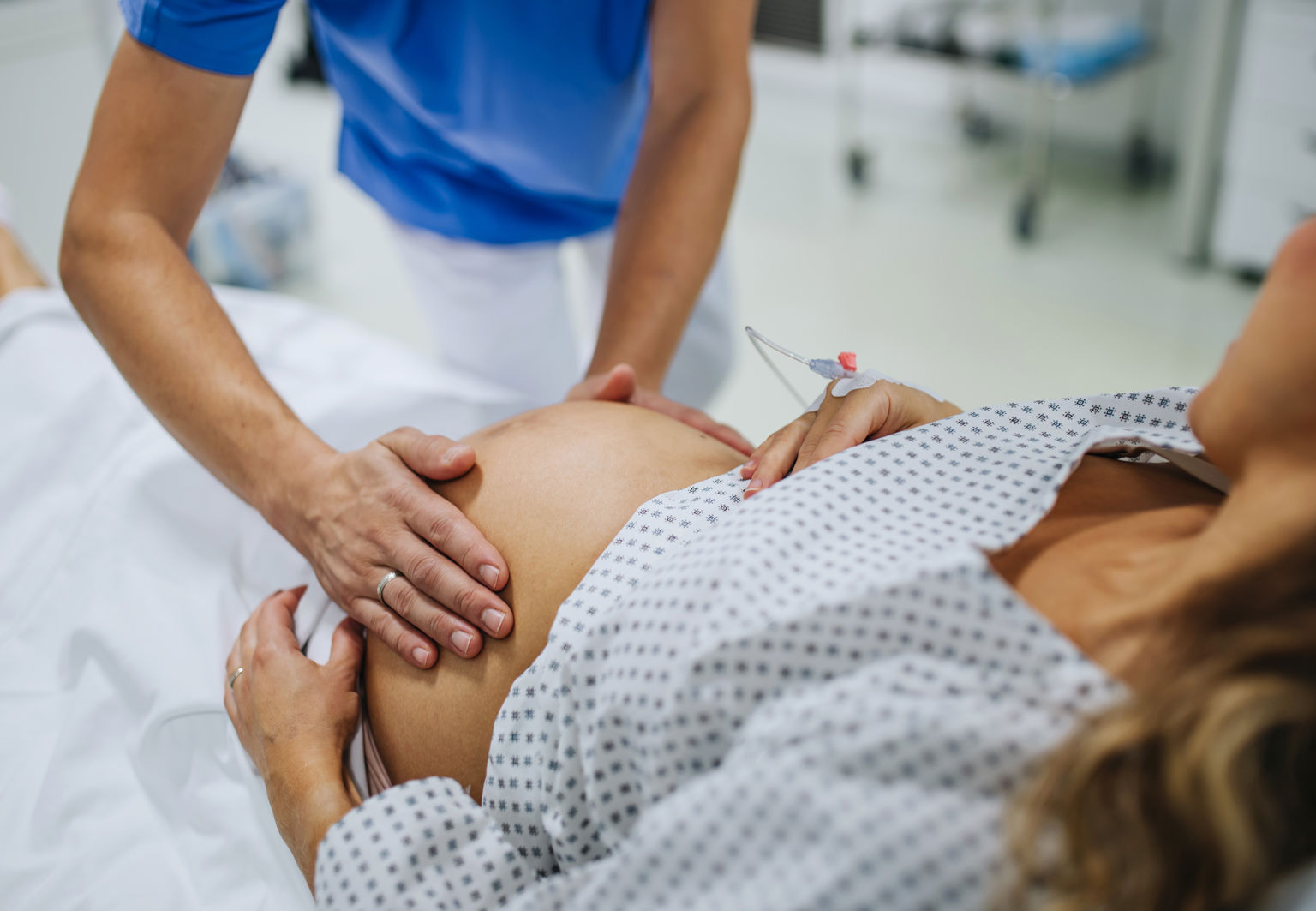 Barnmorska tar på gravid kvinnas mage inne i ett förlossningsrum