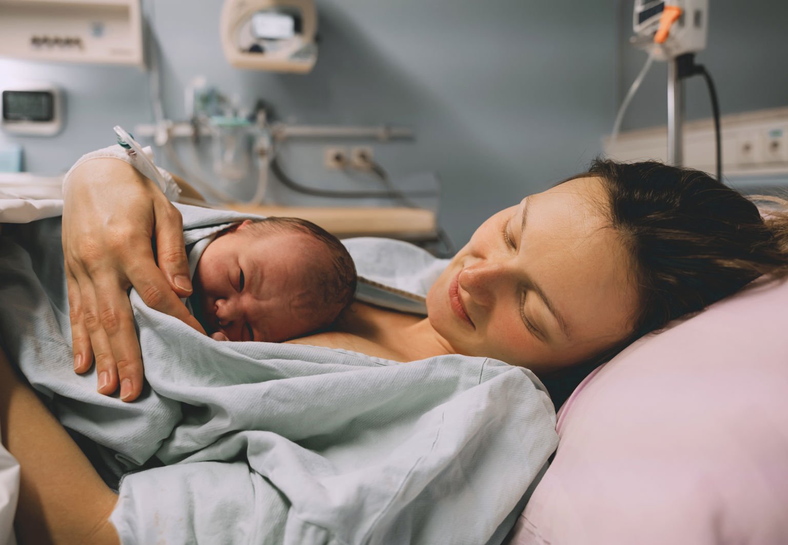 Bebis ligger på kvinnas bröst i förlossningsrum