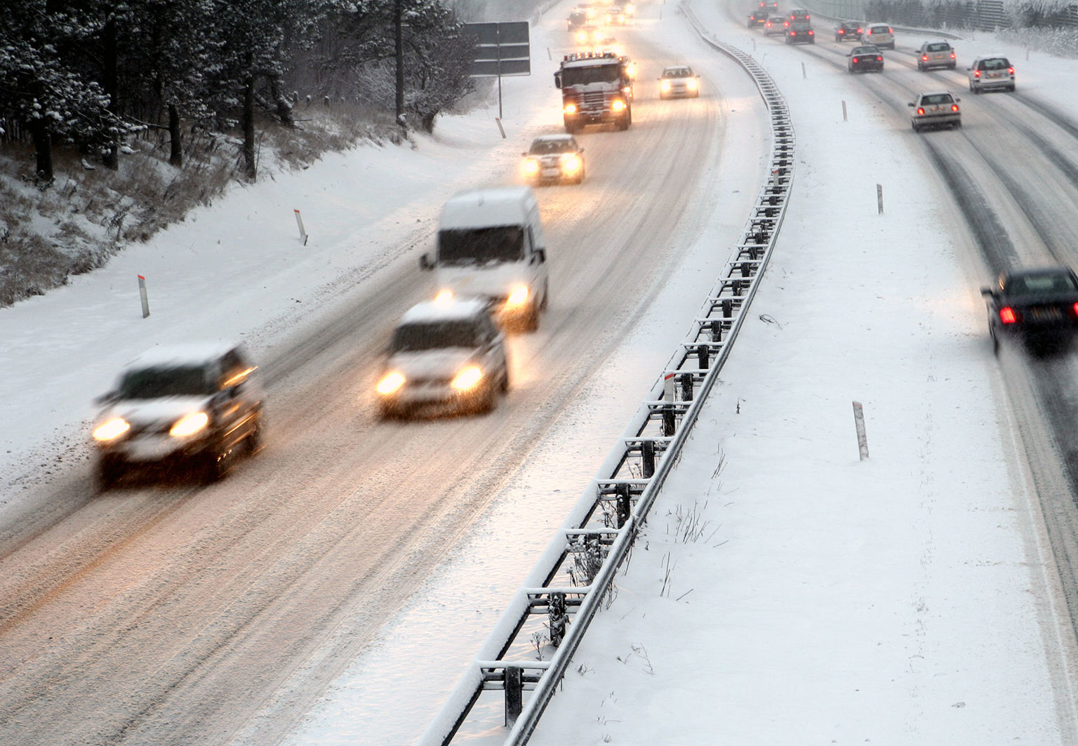 Bilar på en trafikerad och snötäckt motorväg