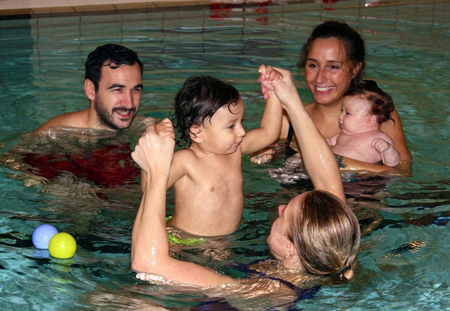 Familj med bebis i en pool inomhus