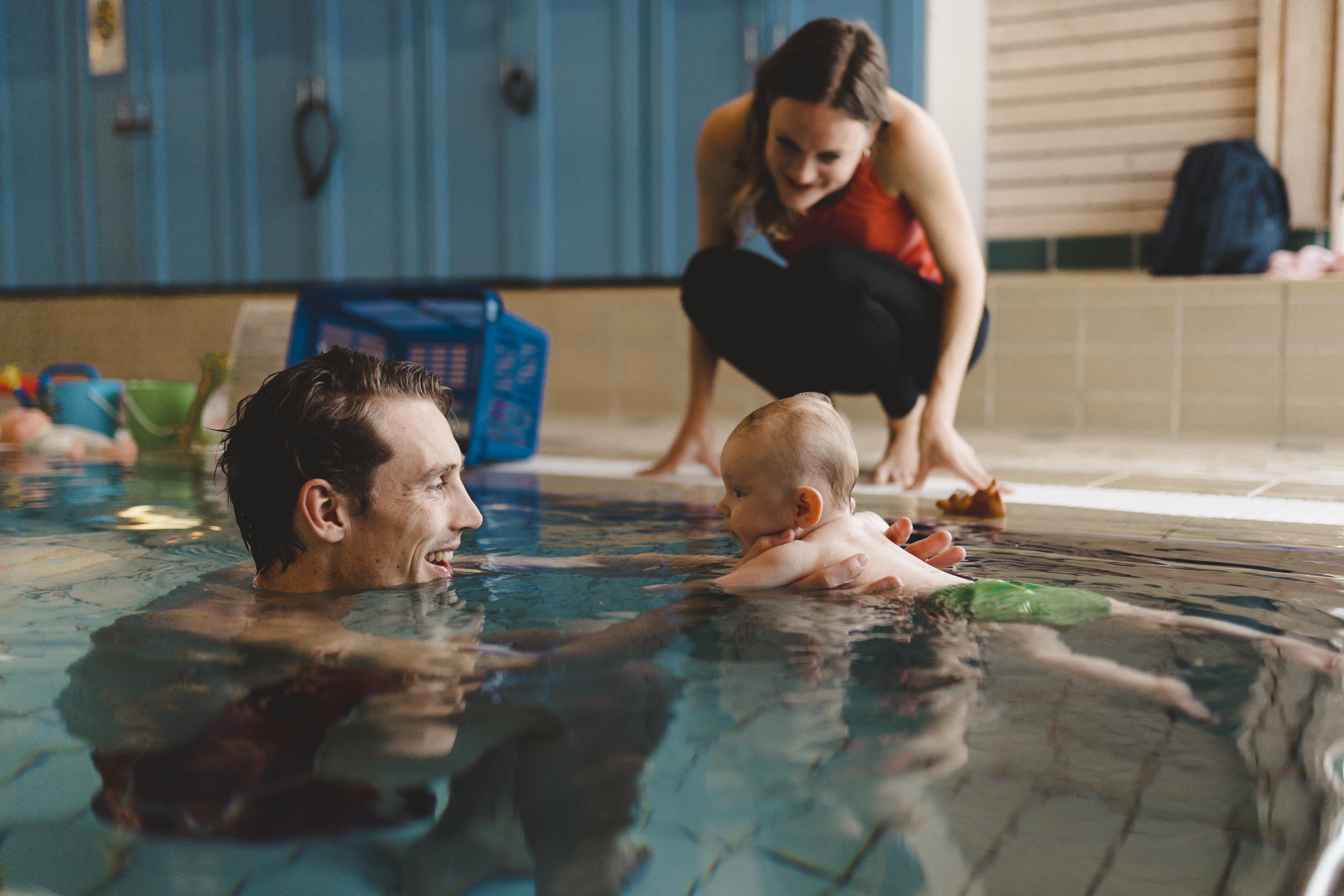 Pappa och bebis leker i en inomhuspool