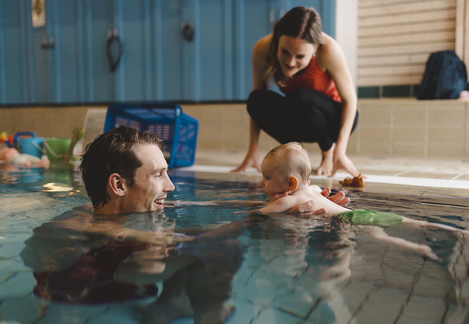 Pappa och bebis leker i en inomhuspool