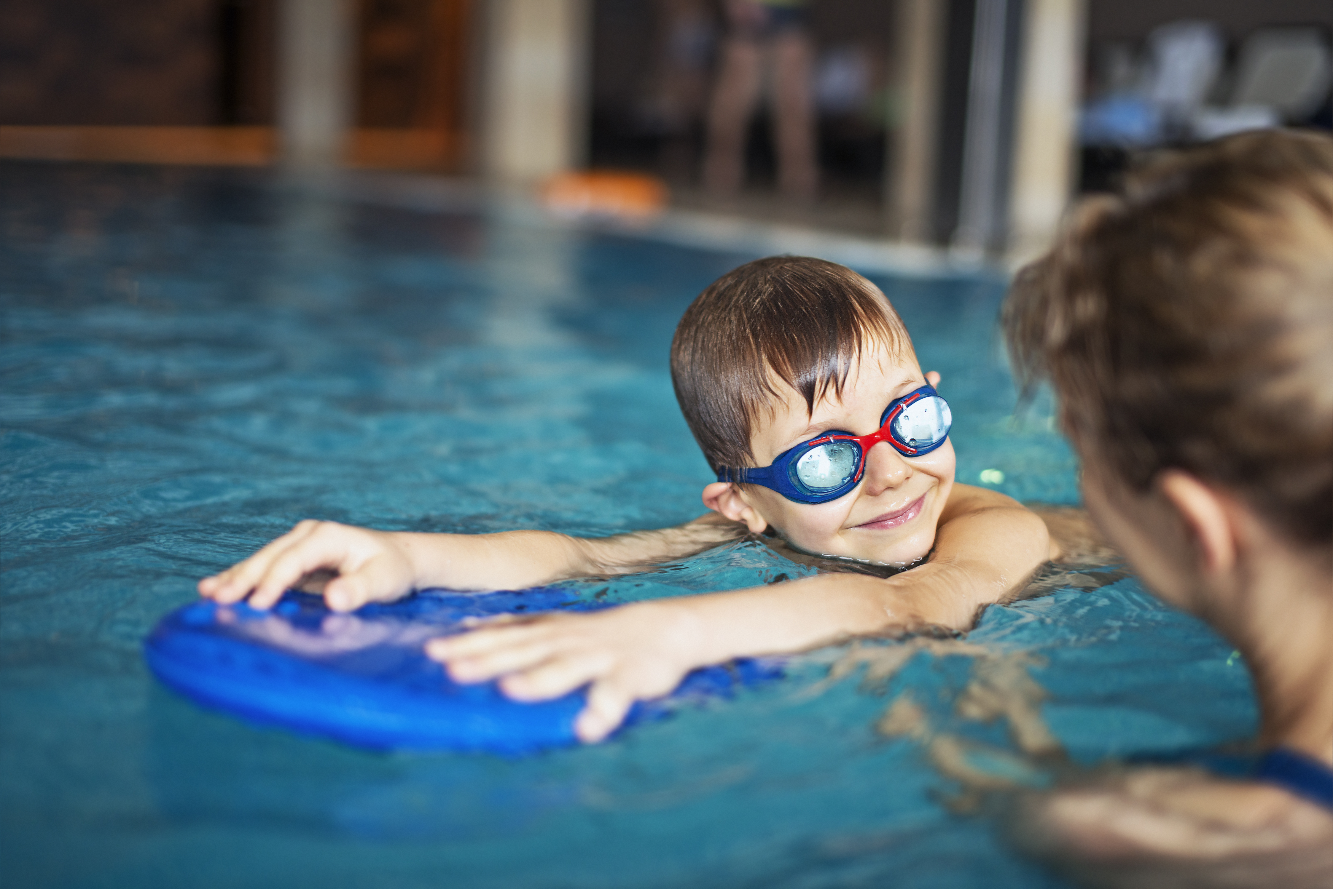 Pojke med simglasögon använder flytkudde i en pool