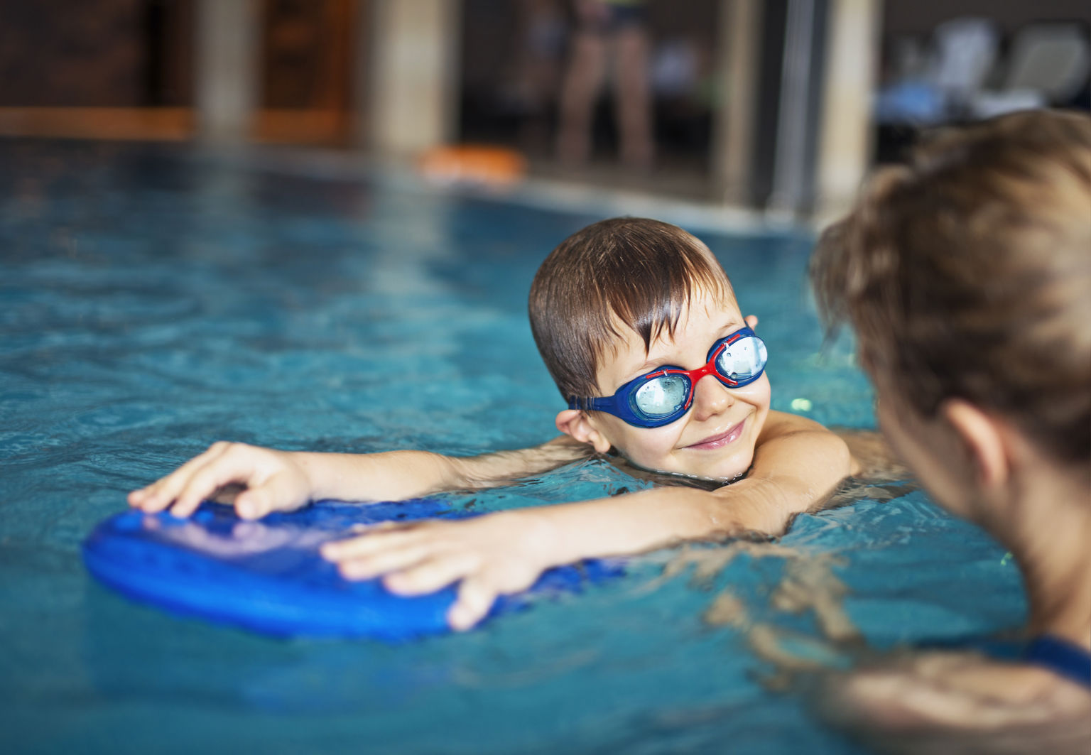 Pojke med simglasögon använder flytkudde i en pool