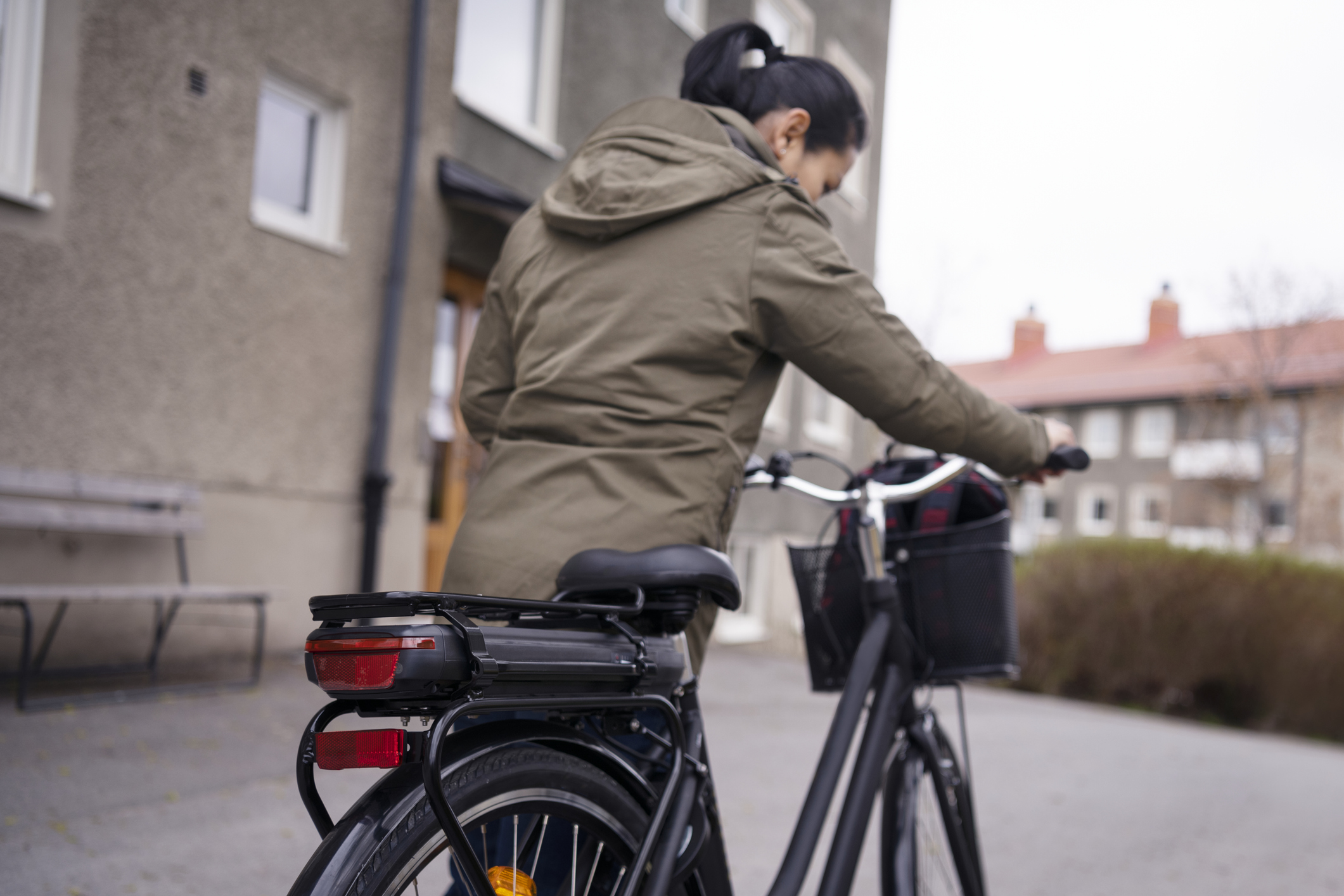 Kvinna leder sin elcykel i ett bostadsområde