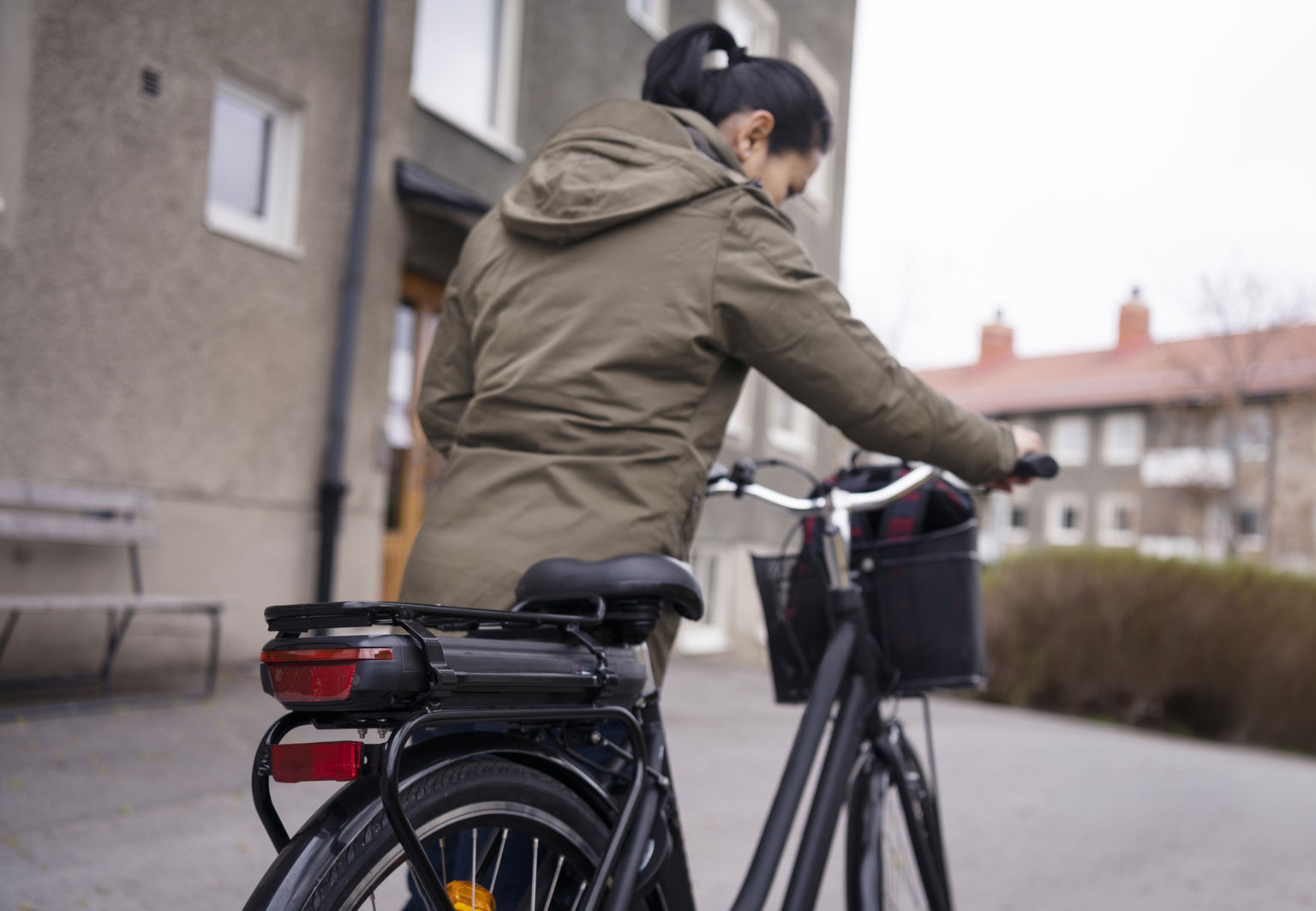 Kvinna leder sin elcykel i ett bostadsområde