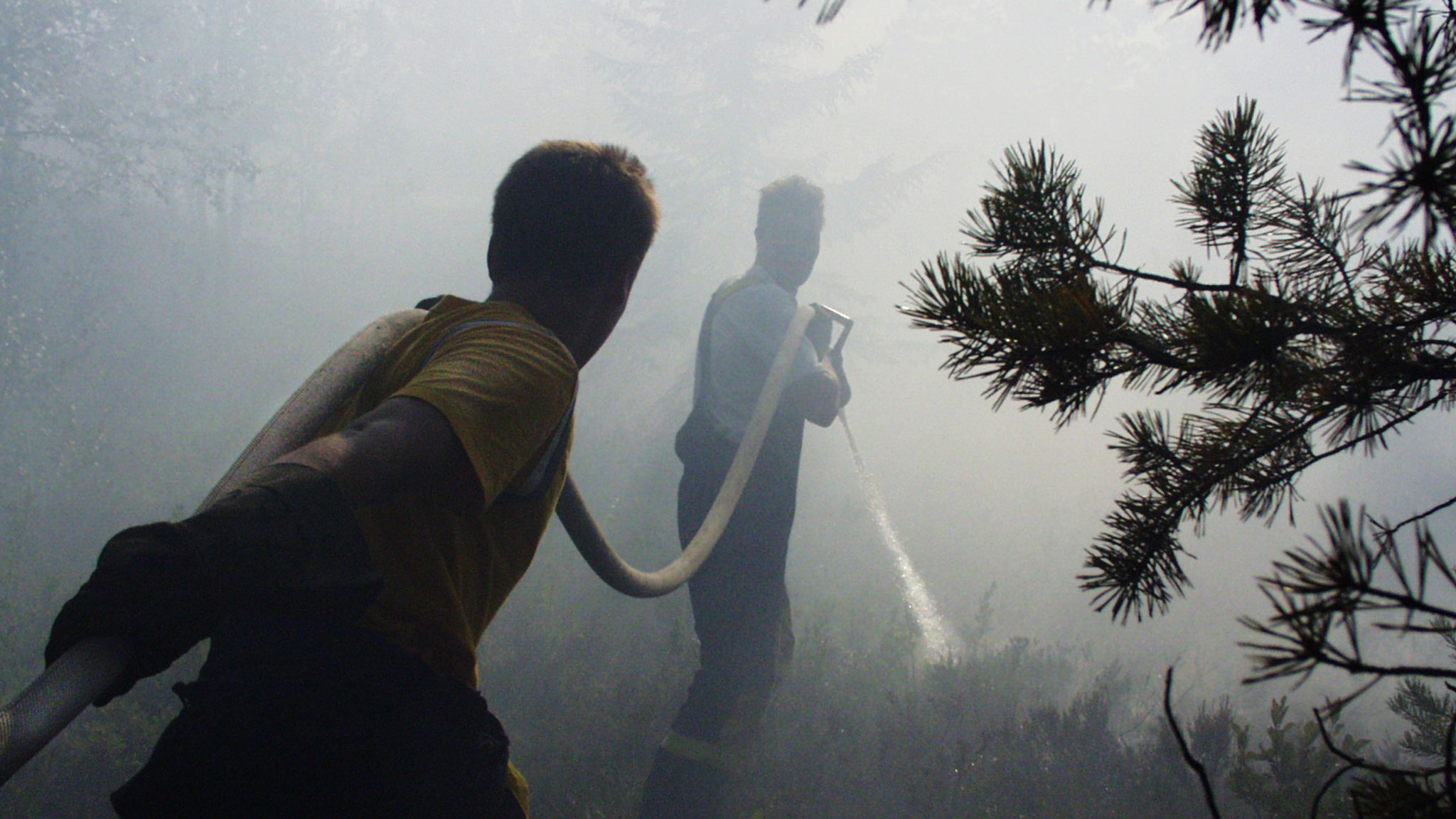 Två personer i rökfyllt område med en brandslang