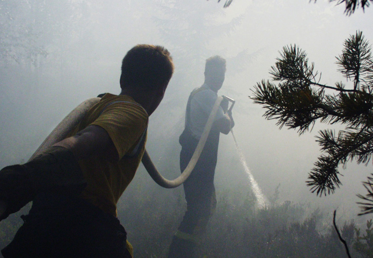 Två personer i rökfyllt område med en brandslang