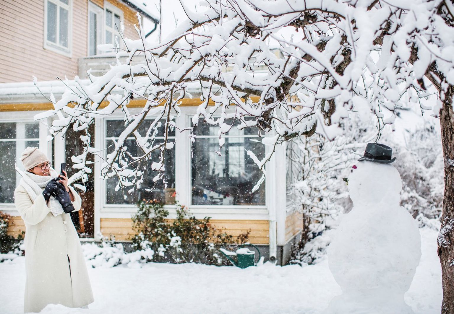 Kvinna fotar snögubbe på tomten