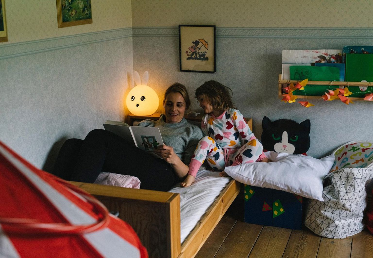 Kvinna och flicka läser godnattsaga i sängen