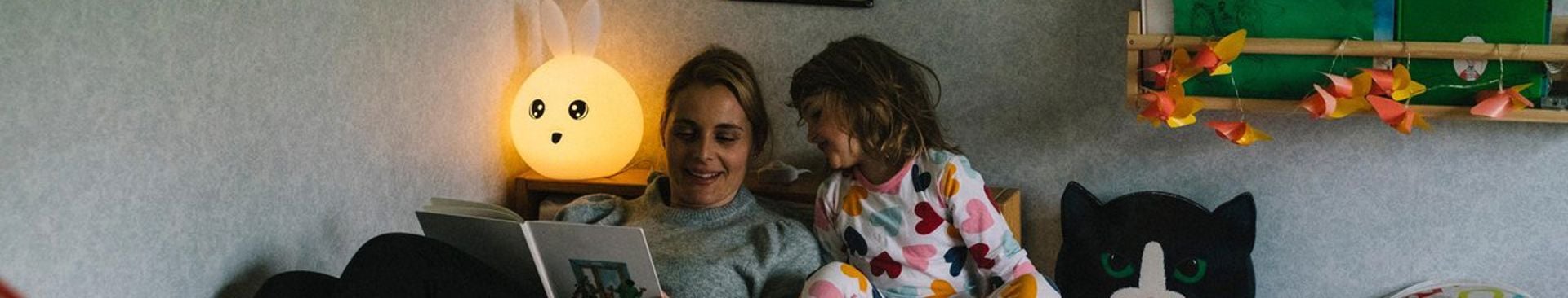 Kvinna och flicka läser godnattsaga i sängen