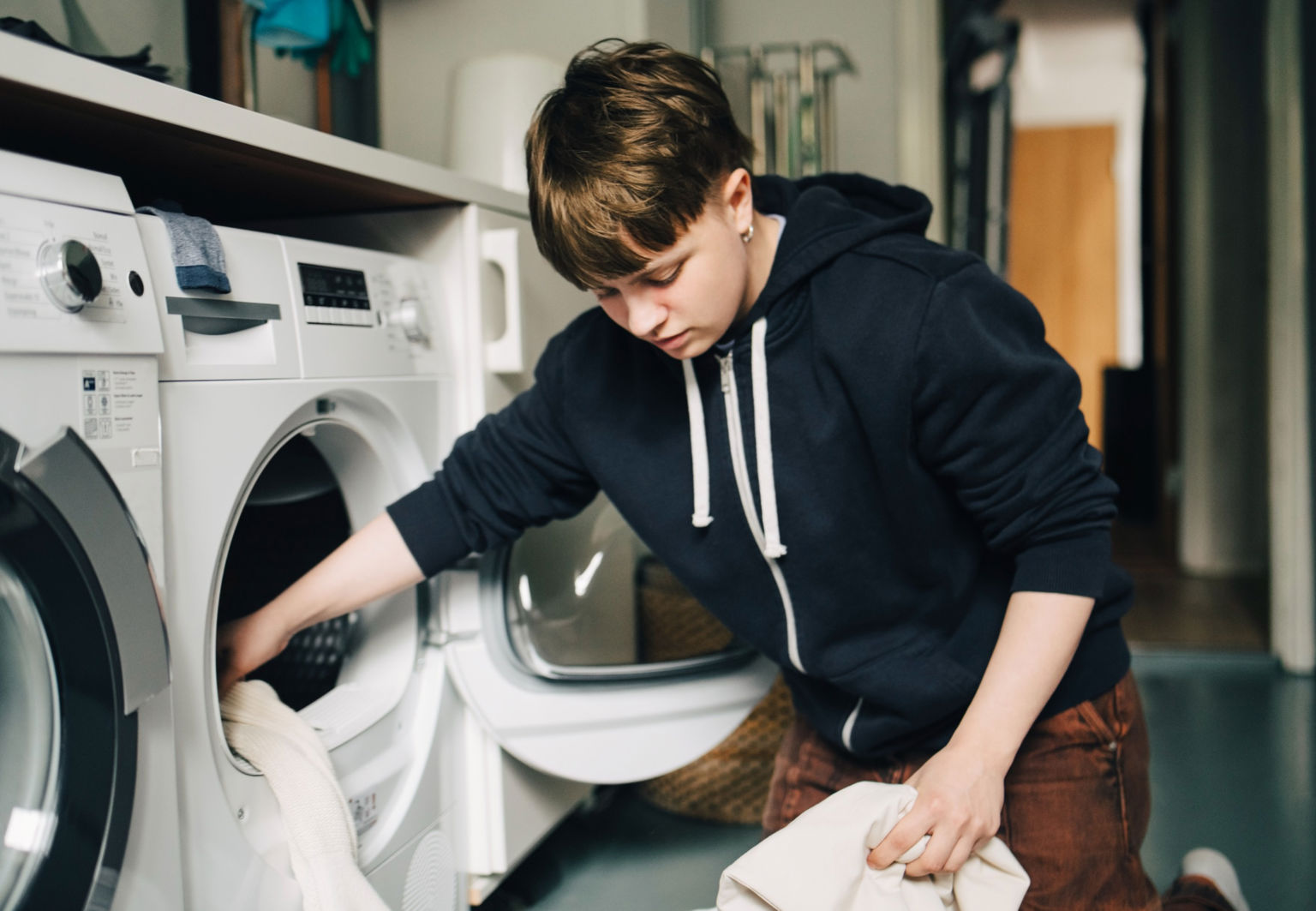Ungdom lägger in tvätt i tvättmaskinen