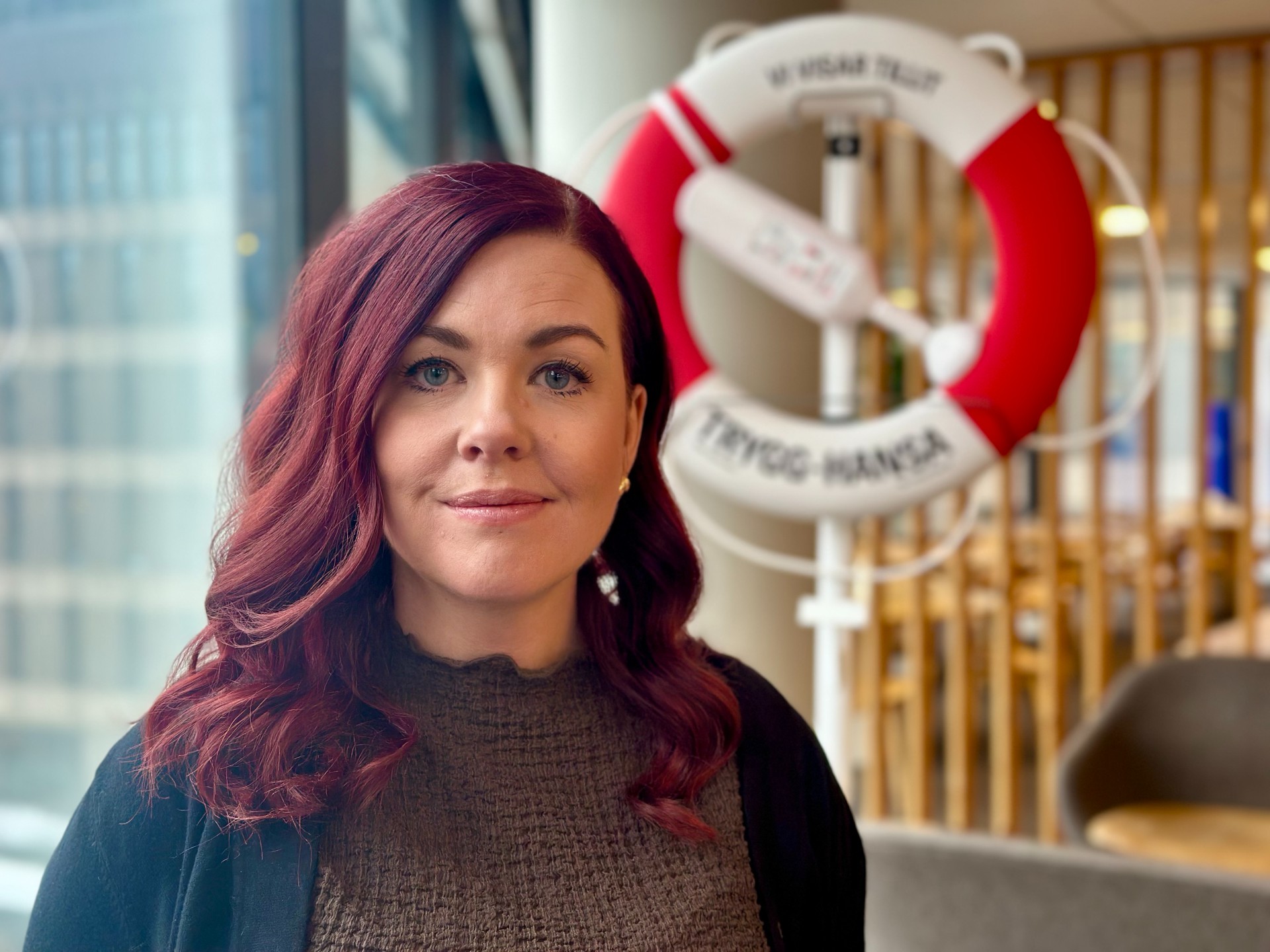 Vår barnmorska Anna står framför en livboj på Trygg-Hansas kontor