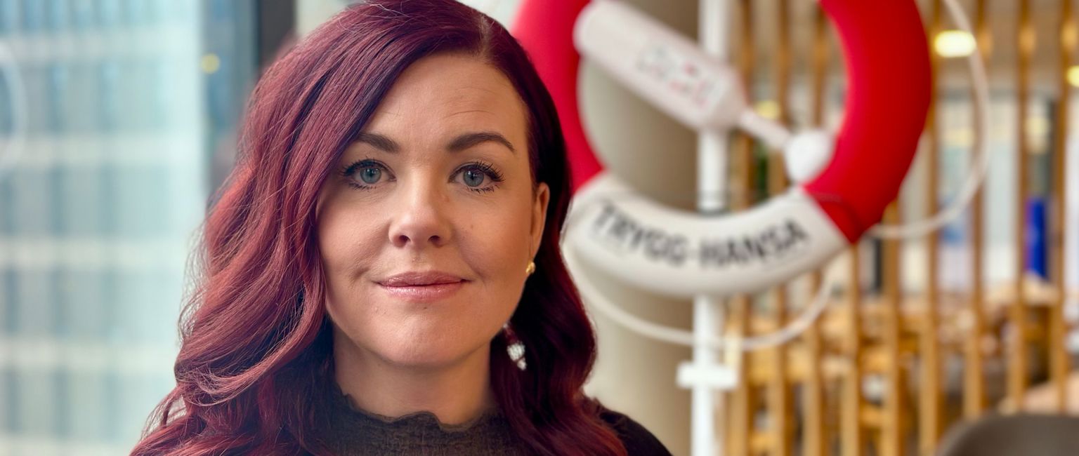 Vår barnmorska Anna står framför en livboj på Trygg-Hansas kontor