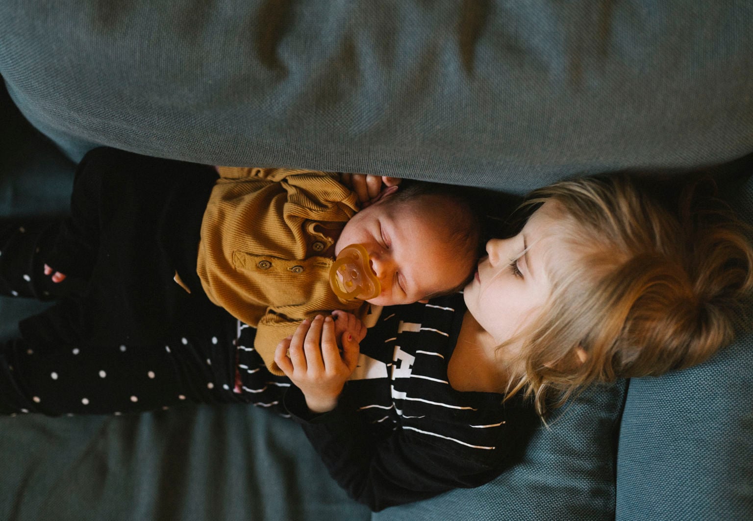 Storasyskon och bebis kramas i en soffa