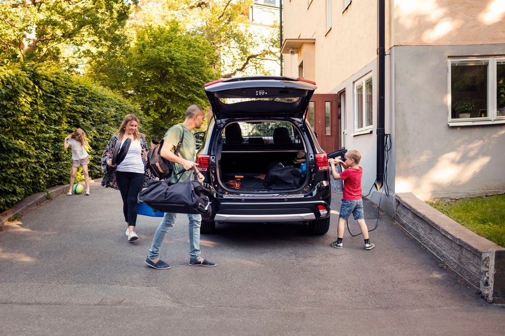 Föräldrar och barn packar in väskor i bagageutrymmet på bilen