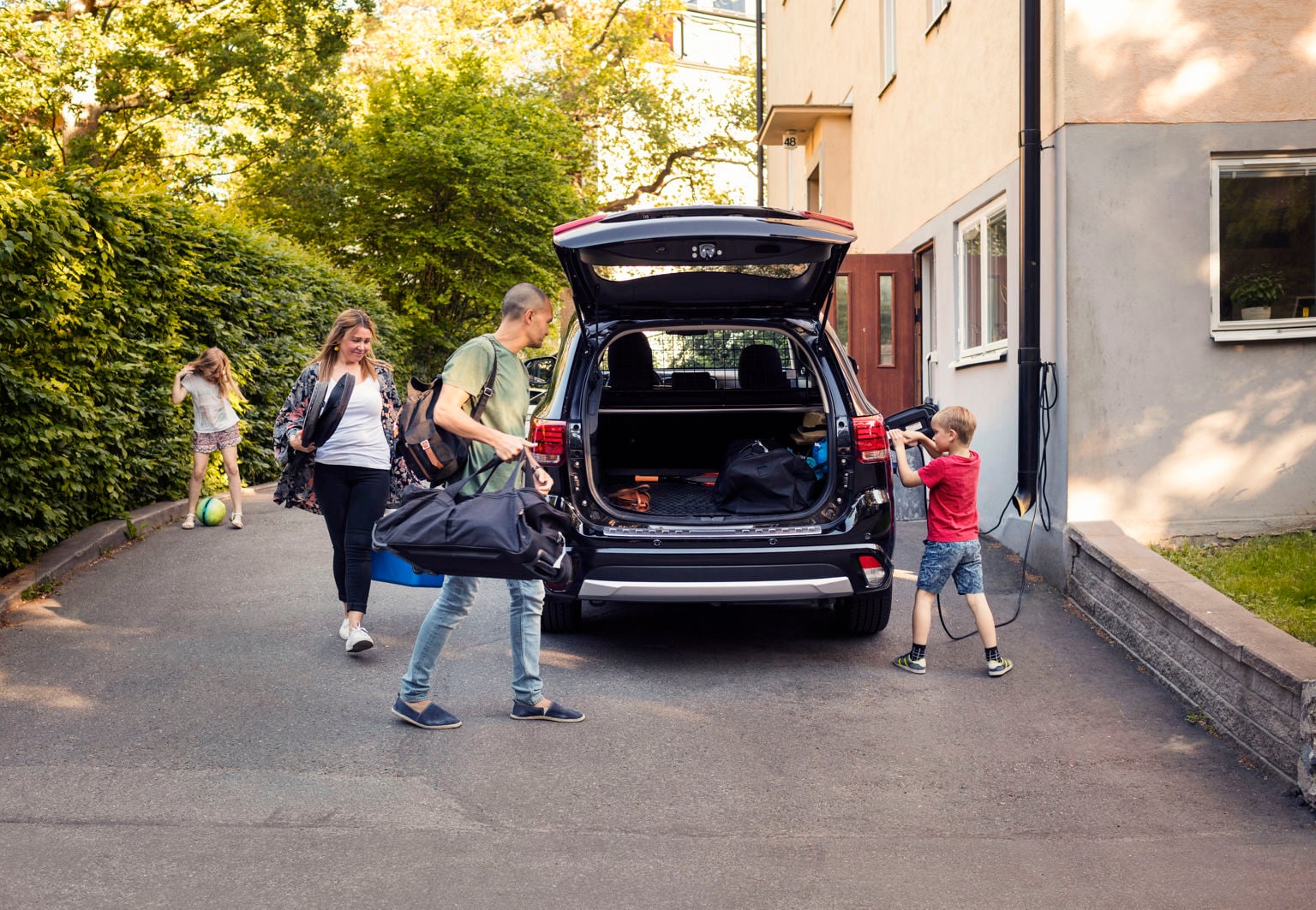 Föräldrar och barn packar in väskor i bagageutrymmet på bilen