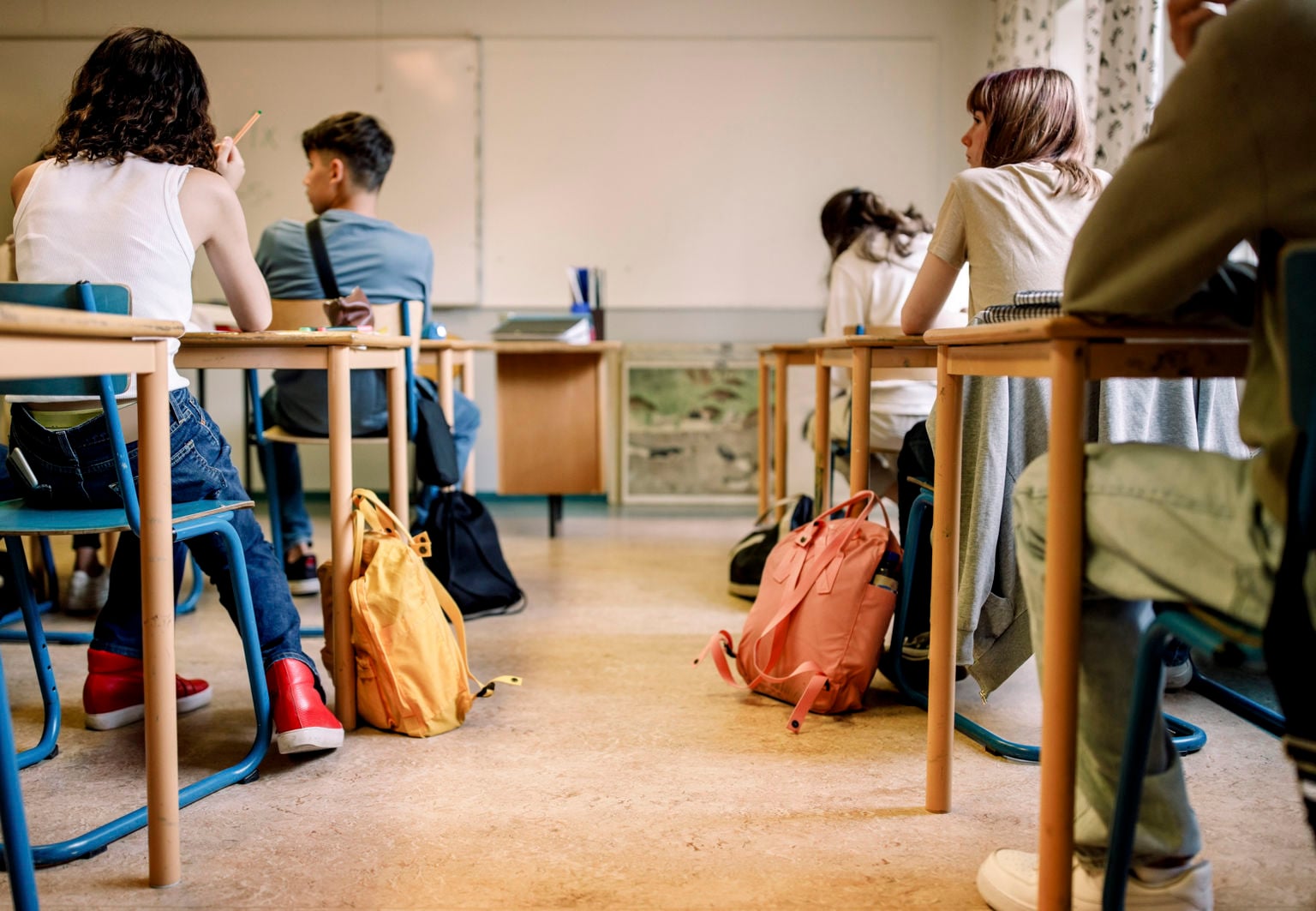 Flera ungdomar sitter i ett klassrum med tillhörande väskor på golvet
