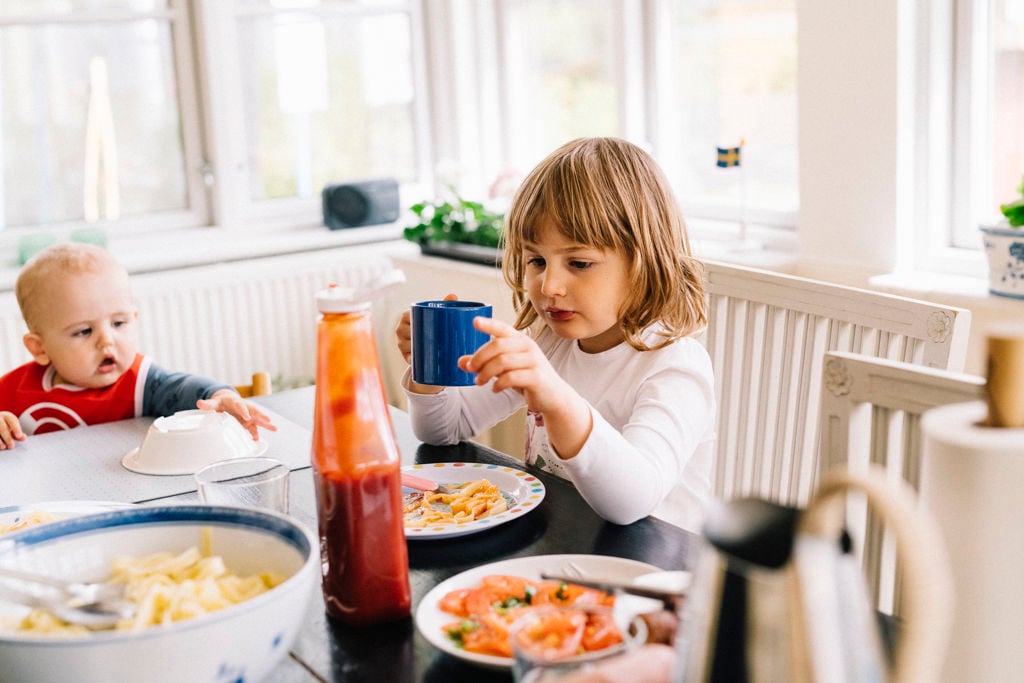 Två barn varav en bebis sitter vid ett matbord