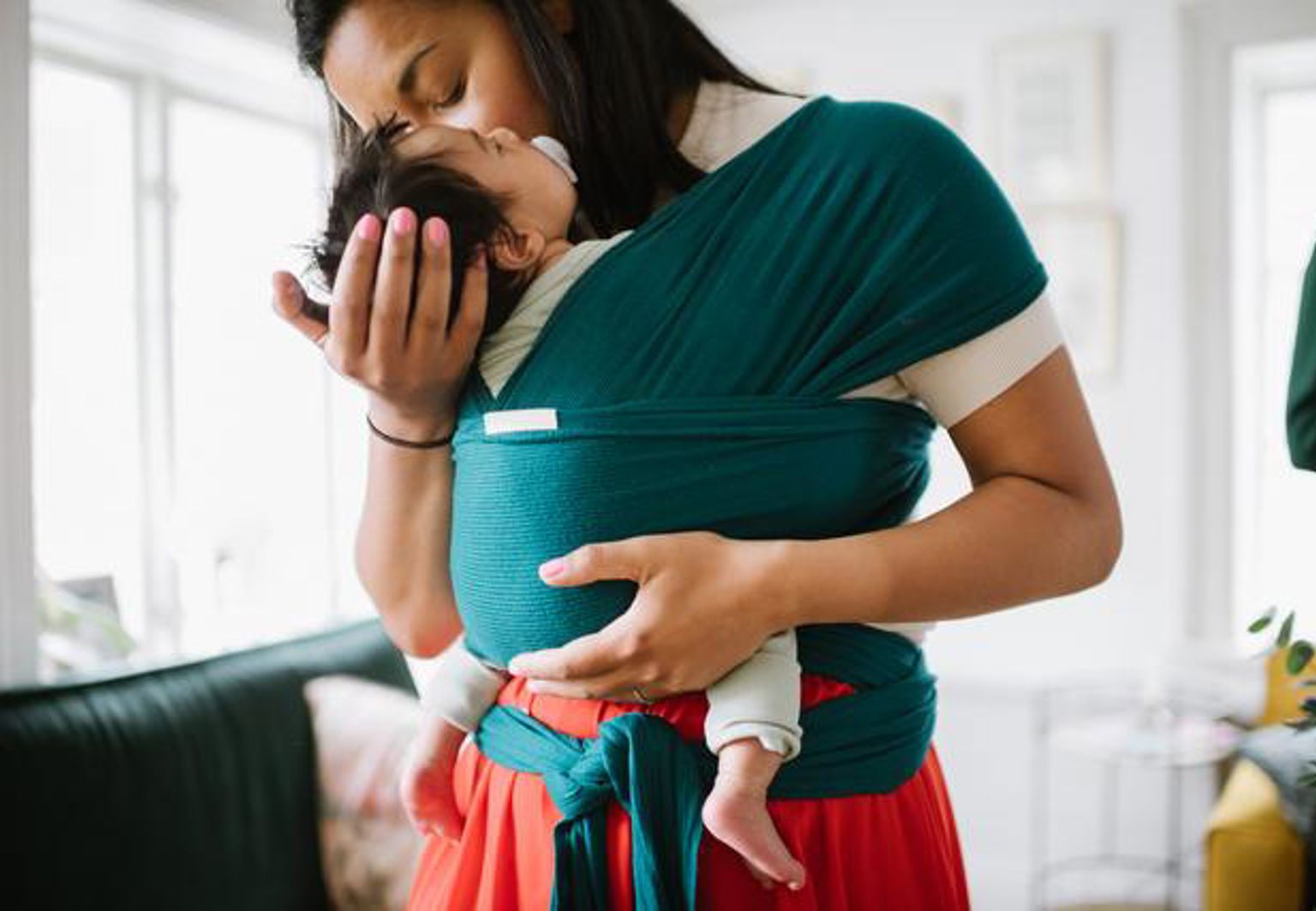 Mamma har en bebis i en bärsjal och myser kind mot kind