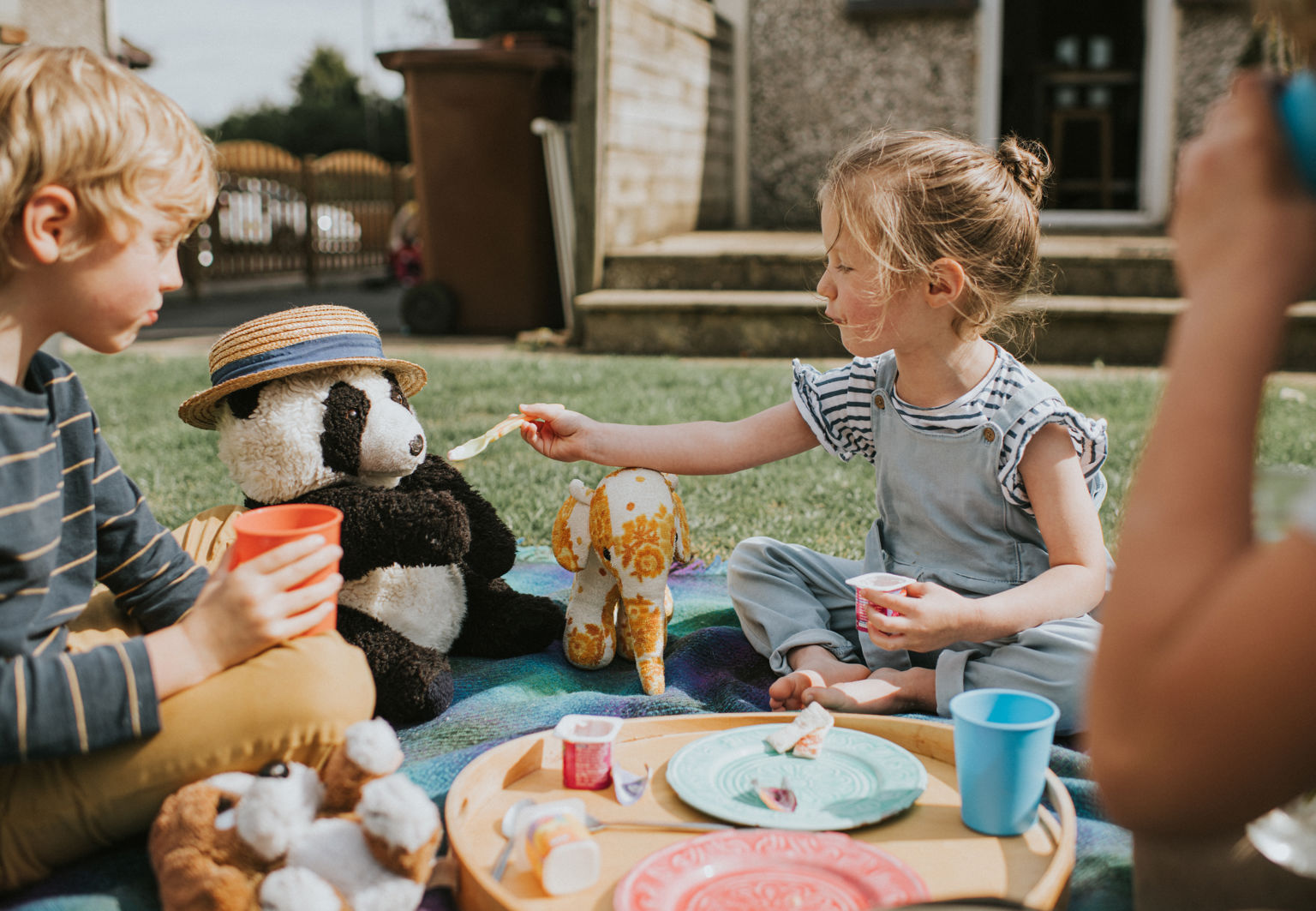 Barn har picknick och en flicka matar sitt gosedjur med sked