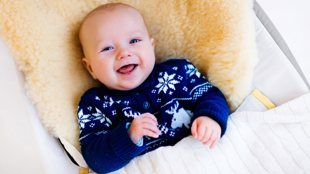 Glad bebis sitter i en babysitter