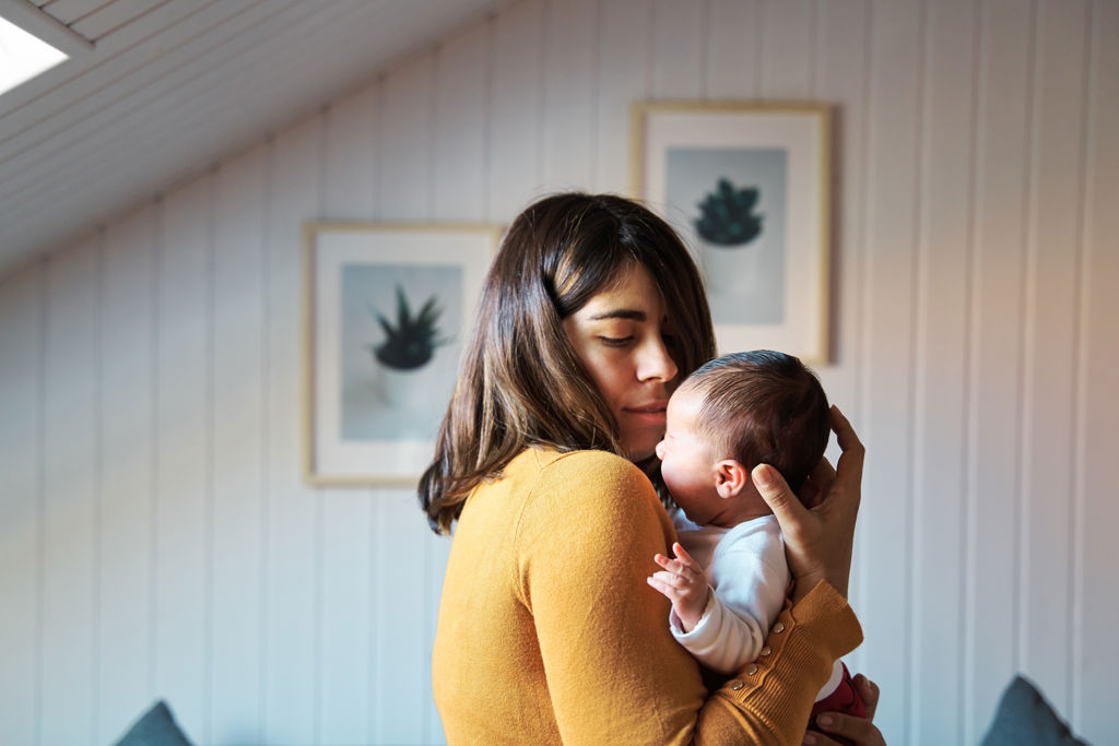 Mamma håller om och tittar på sin nyfödda bebis i hemmamiljö