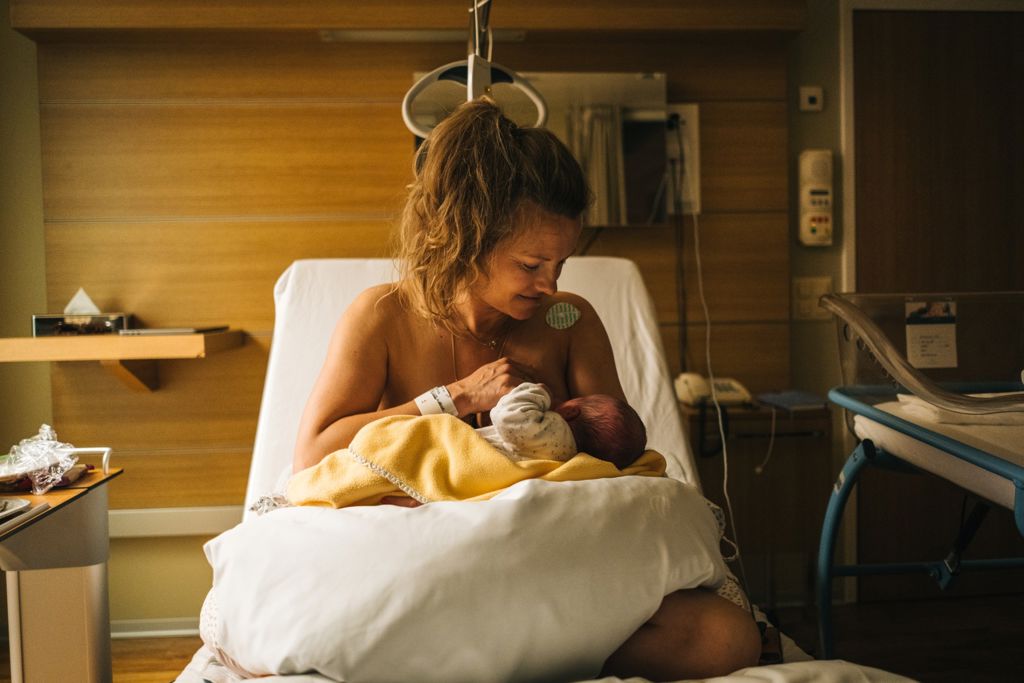 Kvinna ammar sin nyfödda bebis i sjukhussäng på BB