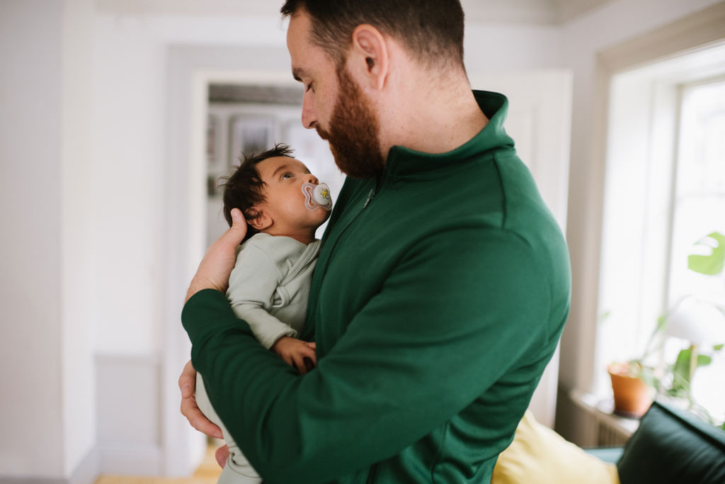 Pappa håller i en bebis som har en napp i munnen