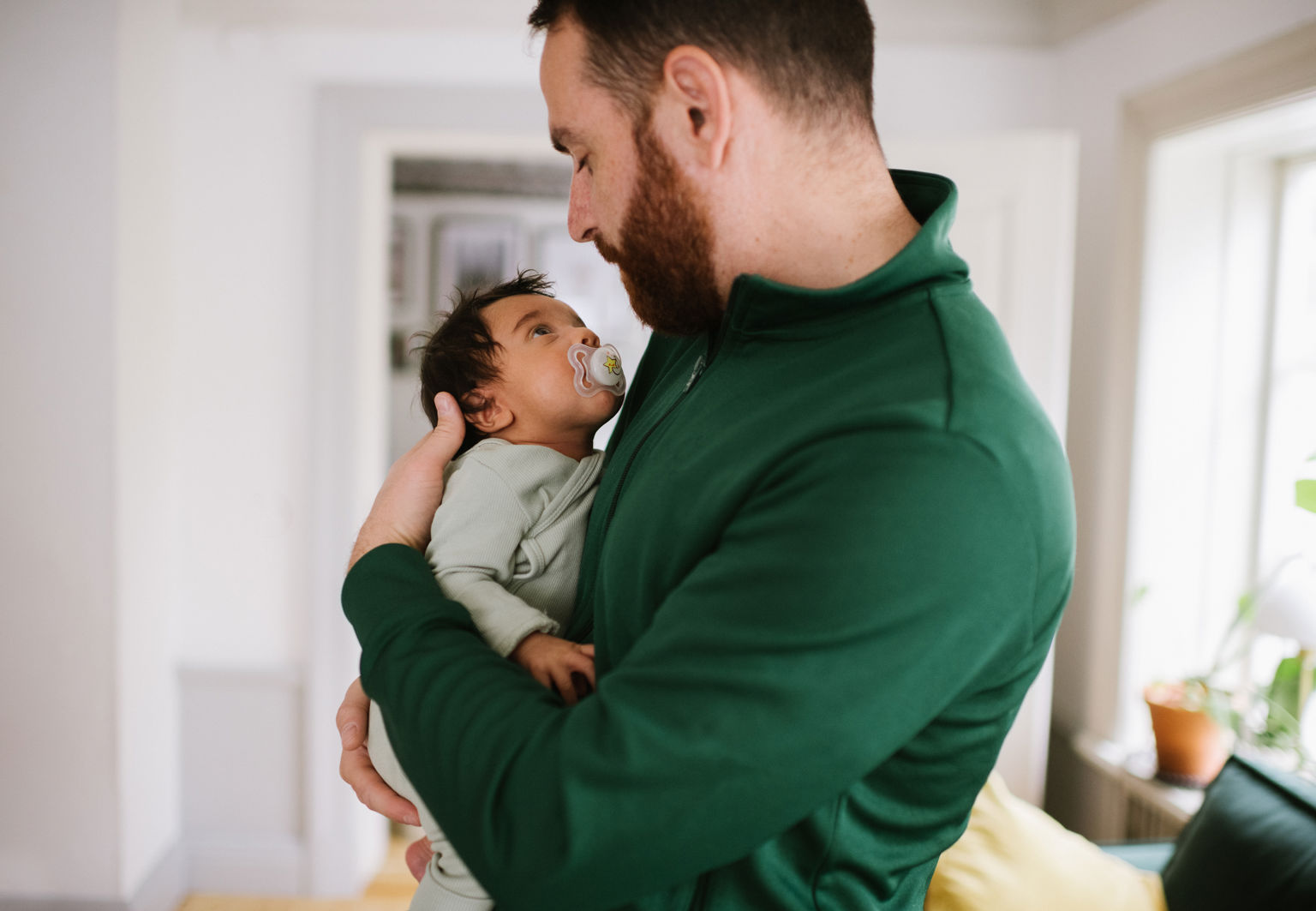 Pappa håller i en bebis som har en nap i munnen