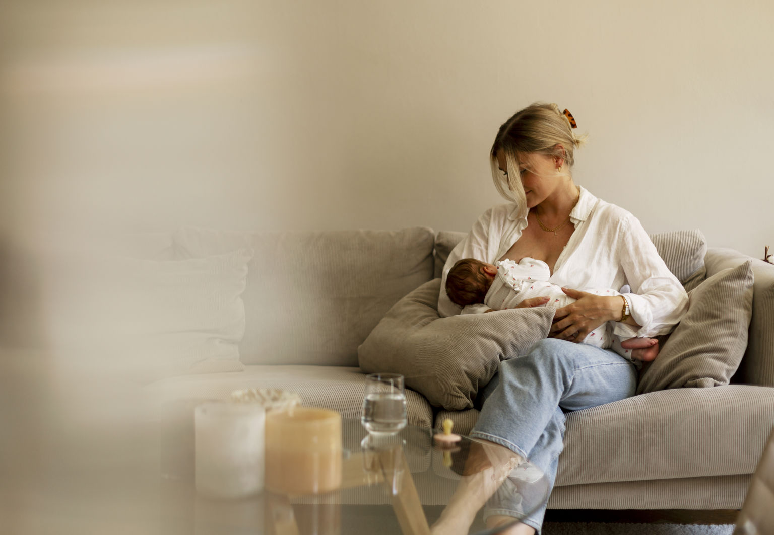 Kvinna sitter i en soffa och ammar sin bebis