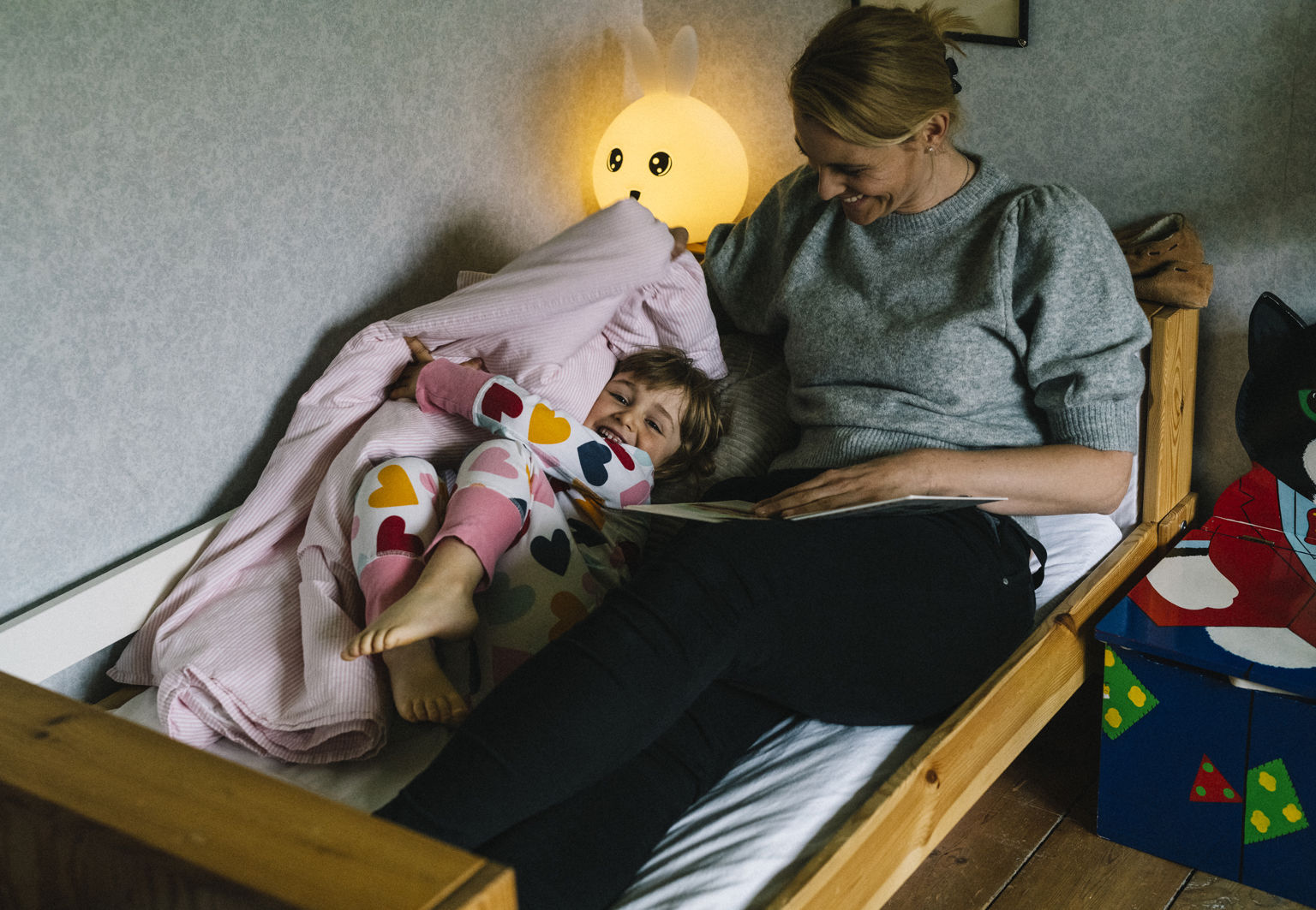 Mamma sitter bredvid sitt barn i en barnsäng