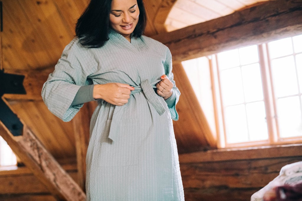 Gravid kvinna knyter åt bandet i midjan på sin morgonrock