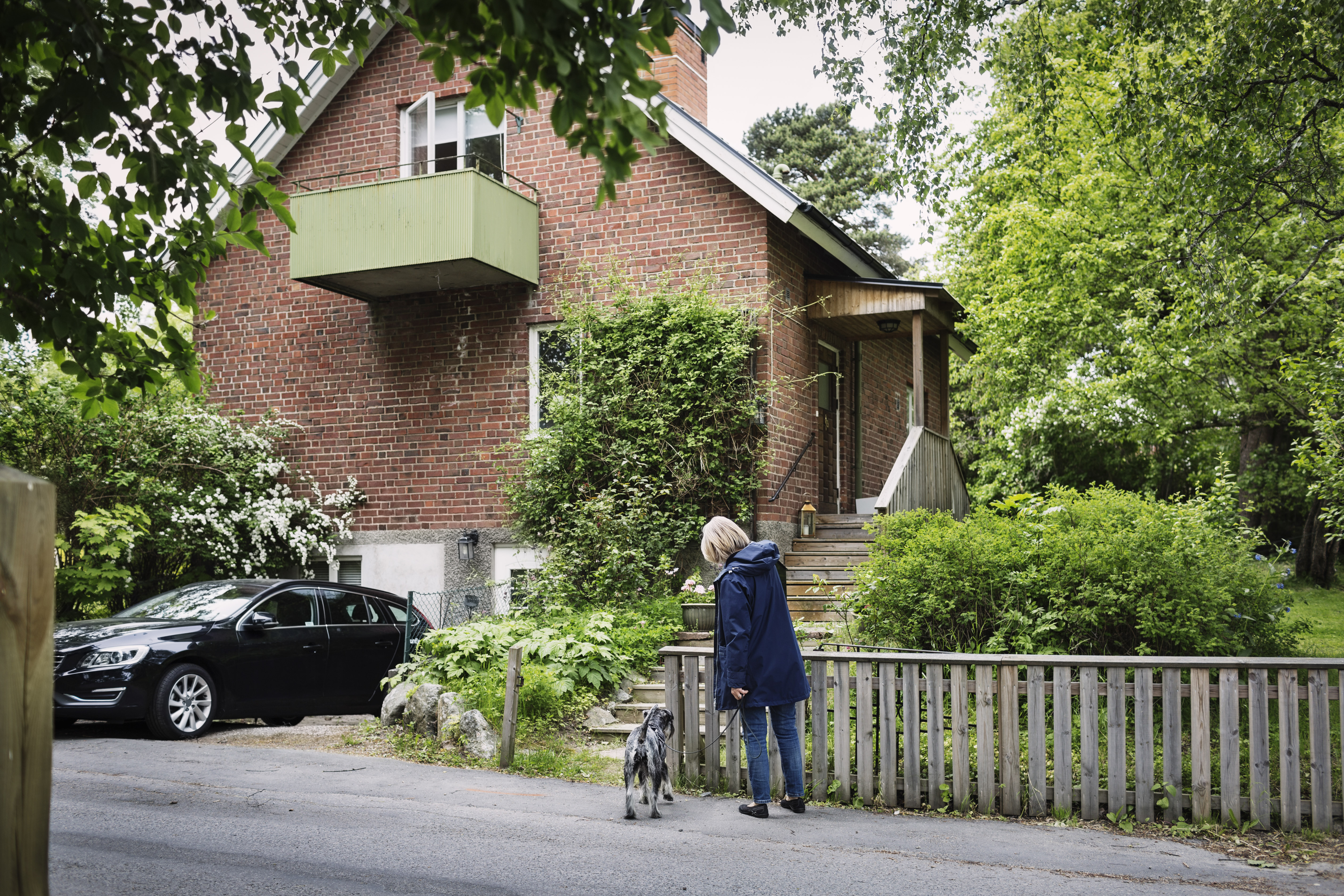 Kvinna med hund står utanför en tegelvilla