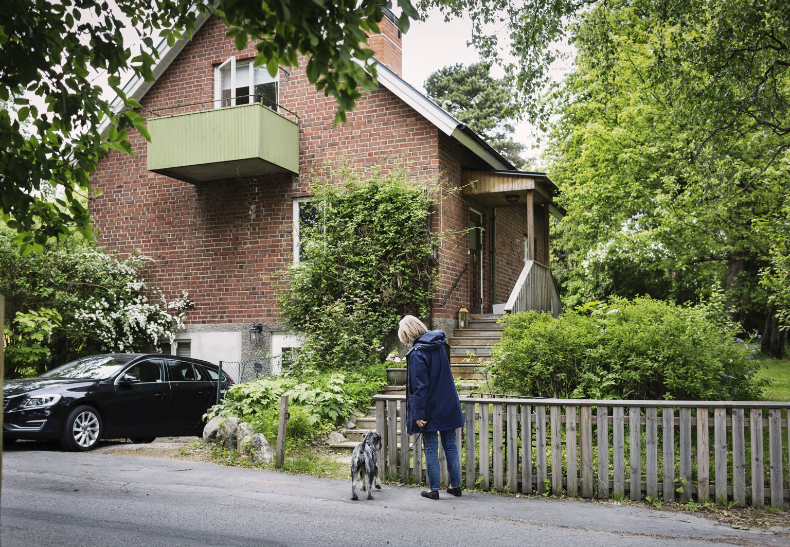 Kvinna med hund står utanför en tegelvilla